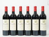 six bouteilles de vin rouge sont alignées sur une surface blanche