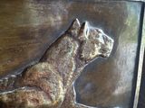 a bronze plaque of a dog sitting on a table