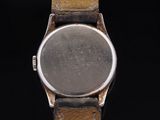 a close up of a watch on a black surface with a black background