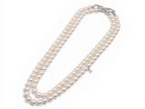 un collier de perles blanches avec un fermoir en argent sur fond blanc