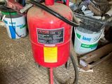 a red fire extinguisor sitting on the floor in a garage