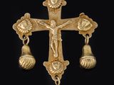 une croix en or à laquelle sont suspendues des clochettes, sur fond noir