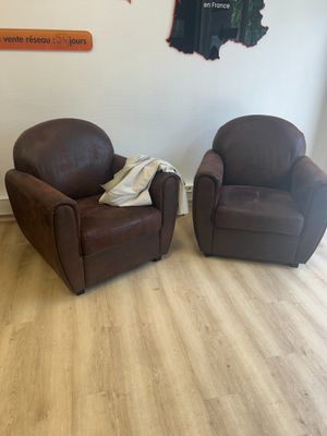 deux fauteuils en cuir marron dans un salon où est accrochée une carte au mur