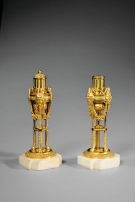 paire de vases plaqués or reposant sur des socles en marbre, posés sur un socle gris
