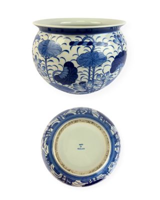 un vase bleu et blanc et une assiette posés sur une surface blanche