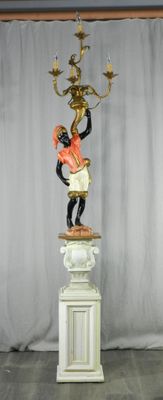 une statue représentant un homme tenant un chandelier, posée sur un socle