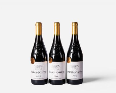 three bottles of wine sit side by side on a white surface