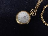 a gold pocket watch with a chain on a black surface