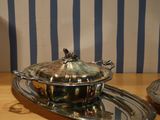 a silver plate with a silver lid on a wooden table