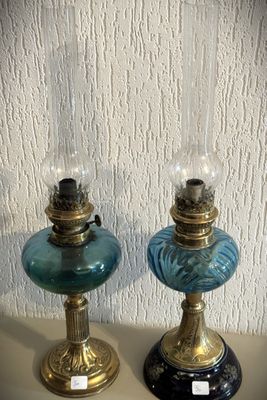 deux lampes en verre bleu posées l'une à côté de l'autre sur une table