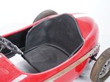 a red pedal car with a black seat and steering wheel