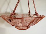 un bol en verre rose suspendu à une corde