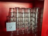 bottles and glasses are stacked on a shelf in a red room