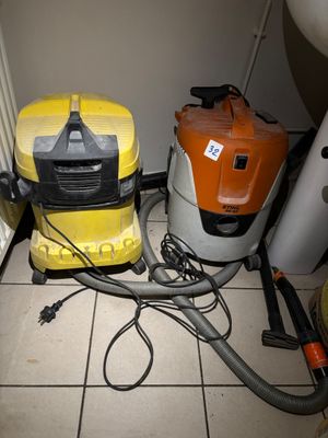 two vacuums that are sitting on the floor next to a toilet