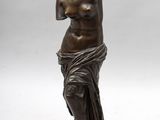 une statue en bronze représentant une femme debout sur un socle en marbre