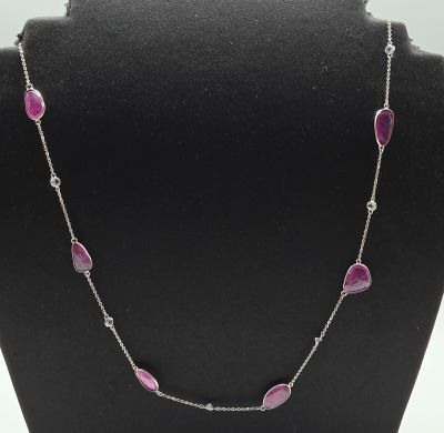 a necklace with pink stones and diamonds on a black mannequin