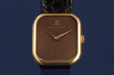 une image montrant un gros plan d'une montre posée sur une surface bleue