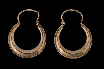 une paire de boucles d'oreilles en or sur fond noir