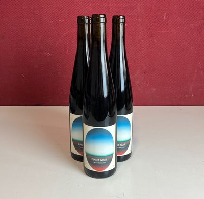 Plusieurs bouteilles de vin sont posées sur une table devant un mur rouge.