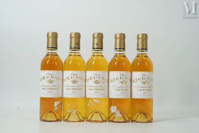 quatre bouteilles de vin sont alignées sur une surface blanche