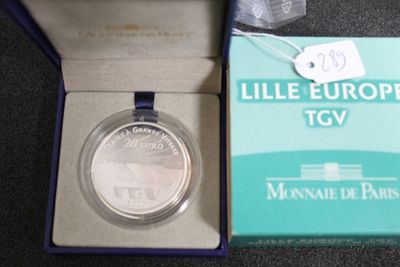 une pièce d'argent dans une boîte bleue sur laquelle est accrochée une étiquette