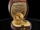 an image of a gold ring in a box on a black surface