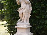 a statue of a boy playing a flute in a garden