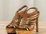brown leather platform sandals with gold straps on a wooden surface