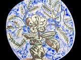 une assiette bleue et blanche sur laquelle est représenté un vase de fleurs