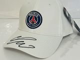 La casquette est blanche et comporte un écusson bleu sur le devant.