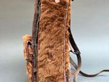 brown leather and fur backpack with strap on grey background