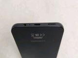 the back of a black cell phone sitting on top of a white surface