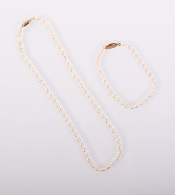 un collier blanc et une chaîne en or sur fond blanc