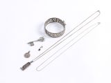 an assortment of silver jewelry on a white surface with a white background