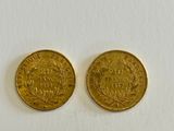 a pair of two gold coins sitting on top of a white surface