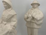 pair of white statues of a man and a woman sitting on a bench