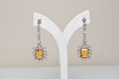a pair of yellow and white earrings on a white stand