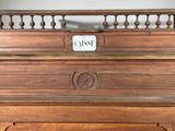 a wooden piano with a sign on the top of it
