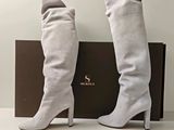 une paire de bottes blanches pour femme, avec une boîte posée sur un fond blanc