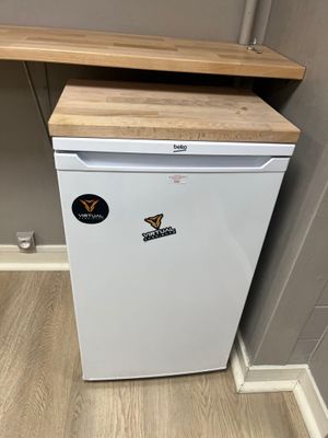 un petit réfrigérateur blanc dans le coin d'une pièce