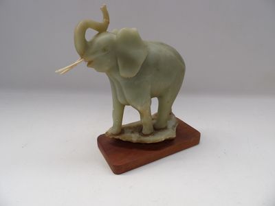 statue d'un éléphant doté d'une longue défense, posée sur un socle en bois