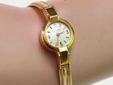 Quelqu'un porte une montre-bracelet en or avec un cadran blanc.