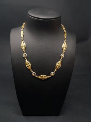 un collier en or sur un mannequin, sur fond noir