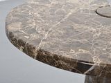 a marble table with a circular top on a gray floor
