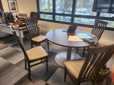 une table avec des chaises et un ordinateur portable posé dessus, dans un bureau