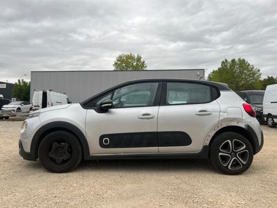 the small car is parked in a lot with other cars in the background
