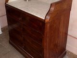 a wooden dresser with a marble top in a room