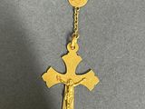 a gold cross necklace with a coin on it
