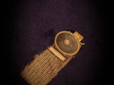 a close up of a watch on a purple surface with a black background