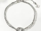 Le bracelet est en métal argenté et présente un motif circulaire.